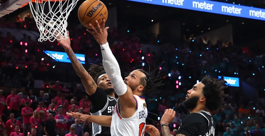 Jalen Brunson #11 of the New York Knicks shoots the ball between Stephon Castle #5 and Julian Champagnie #30 of the San Antonio Spurs during the fourth quarter in Game One of the 2026 NBA Finals at Frost Bank Center on June 03, 2026 in San Antonio, Texas.